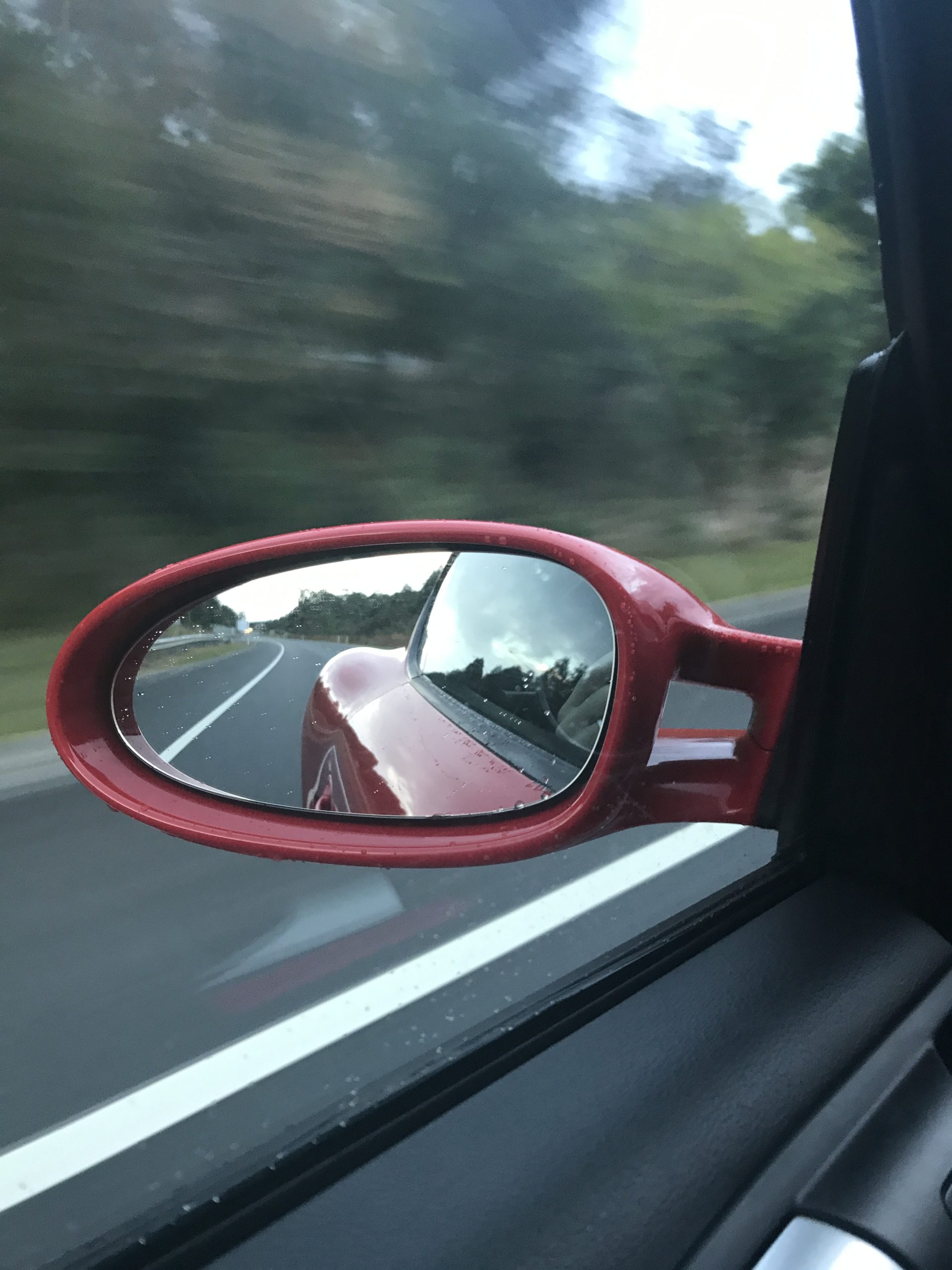 Photo of a panning shot witha side mirror reflecting the road behind